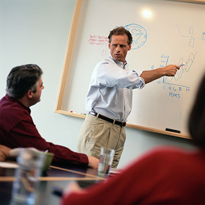 Businessmen discussing items on a whiteboard