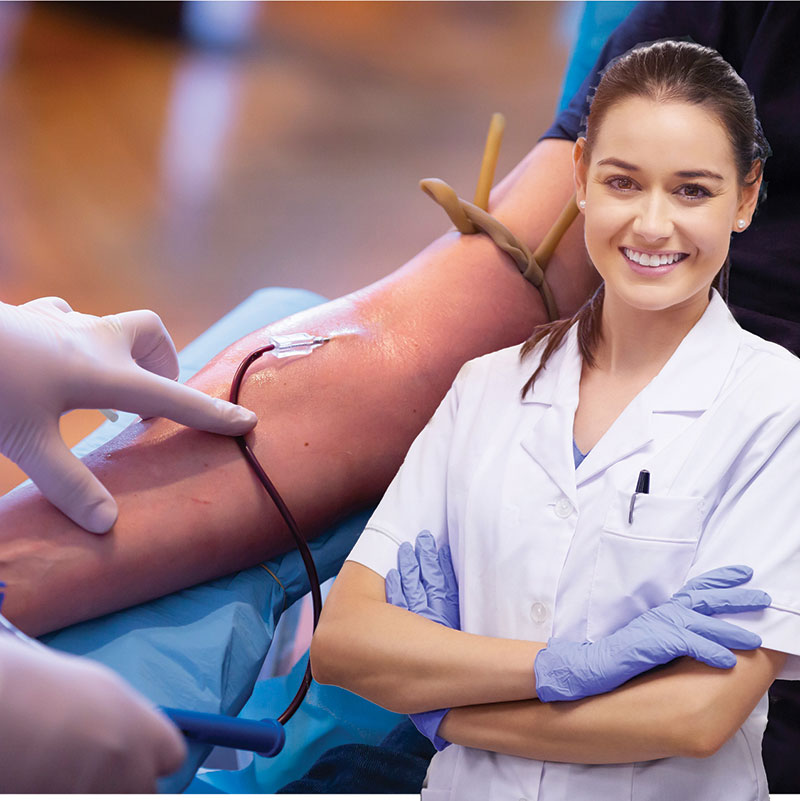 Phlebotomist with needle in arm